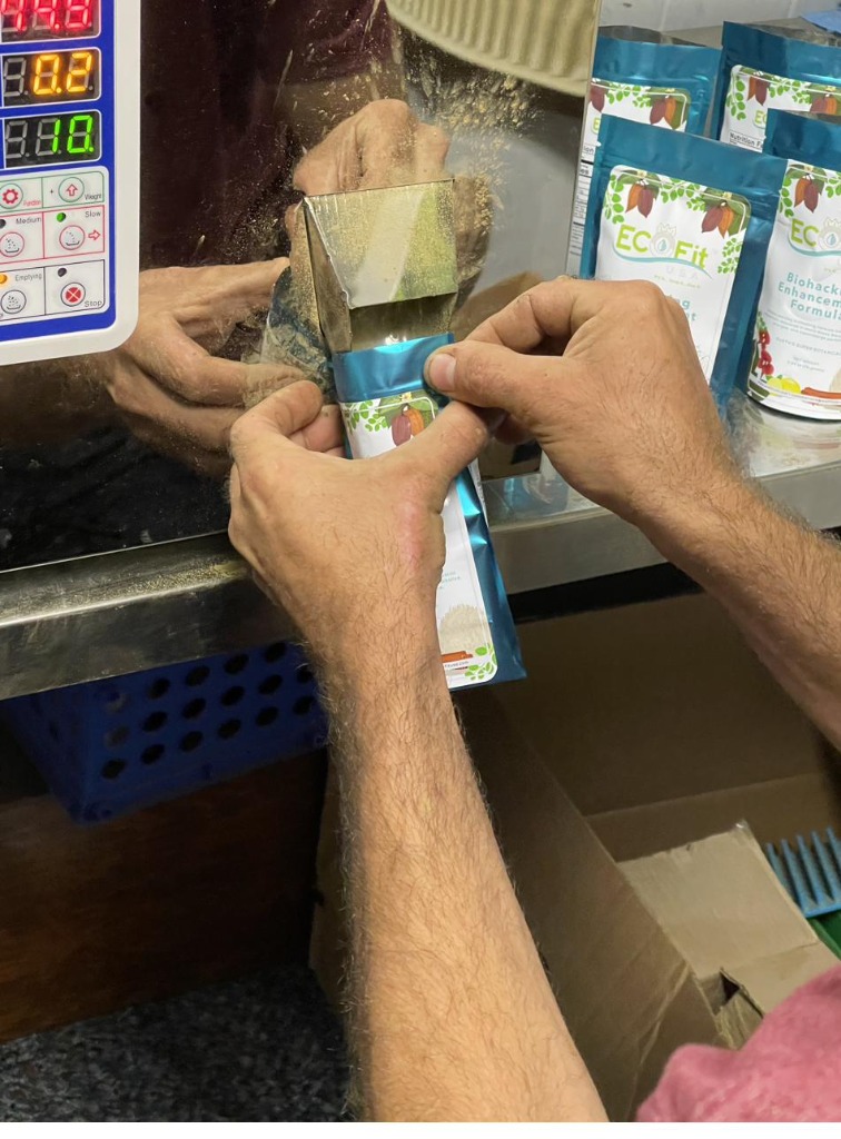 Hands filling and sealing EcoFit bags in the workshop